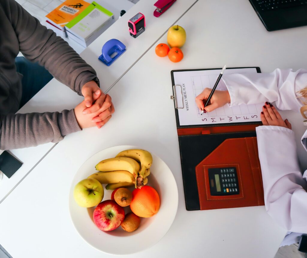 Top view of a dietitian planning a healthy diet with fresh fruits on the table, focusing on health and nutrition.